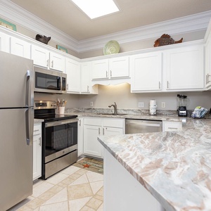 Bright white cabinetry complements the elegant countertops in this modern kitchen, featuring stainless appliances