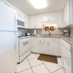 This kitchen features sleek white cabinetry, granite countertops, and modern appliances, perfect for meal preparation