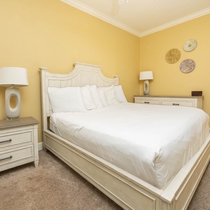 Guest bedroom featuring a plush king bed, stylish lamp, and cheerful yellow walls for a cozy retreat