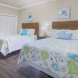 Relax in this guets bedroom featuring two comfortable queen beds, coastal decor, and ample storage for your belongings