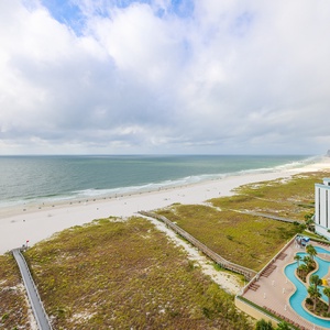 This stunning view showcases a beachfront landscape with a winding pool area and a serene atmosphere for relaxation