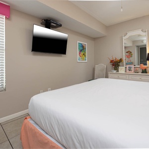 This inviting bedroom features a large bed, stylish decor, and a flat-screen TV for a relaxing stay