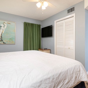 Relax in the serene king suite featuring a plush bed, a TV, and calming decor highlighted by soft green curtains
