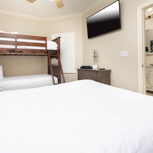 Enjoy a restful stay in this guest bedroom featuring a twin bunk bed, a double bed, and a TV for entertainment