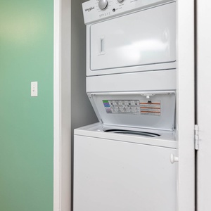 The laundry area features a stacked washer and dryer against a fresh green wall, perfect for convenient in-unit laundry