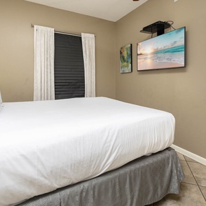 Comfortable guest bedroom featuring a plush queen bed, soft lighting, and a TV for your entertainment