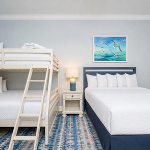 Relax in this cheerful guest bedroom featuring a queen bed, double bed, and twin bunk