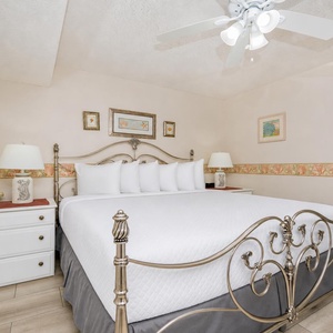 The cozy bedroom features a king bed with white linens, a decorative headboard, and soft lighting from bedside lamps