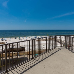 This spacious balcony offers breathtaking views of the sandy beach and vibrant umbrellas, perfect for relaxation