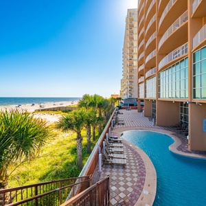 Relax on the sunny deck lined with palm trees and lounge chairs, just steps from the beautiful beach