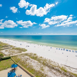 Breathtaking beachfront view showcasing white sand, vibrant umbrellas, and calm turquoise waters under a sunny blue sky