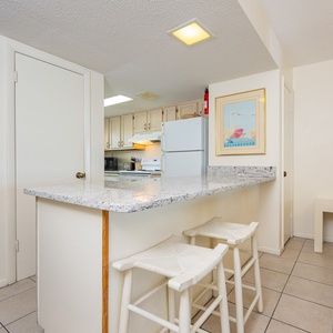 The kitchen features a wooden breakfast bar, white cabinetry, and a cozy seating area, perfect for casual dining