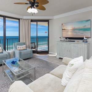 Relax in the spacious living area with plush seating, a large TV, and breathtaking views of the water beyond