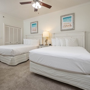 Sleep peacefully in this inviting guest bedroom with two queen beds, soft carpet, and cheerful beach-themed artwork