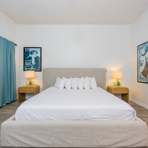 Inviting guest bedroom featuring a plush king bed, two twin bunk beds, stylish artwork, and soft blue curtains