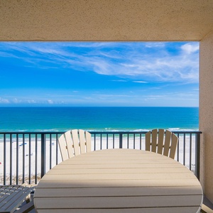 Your balcony offers a serene view of bright blue skies and the gentle coast stretching before you