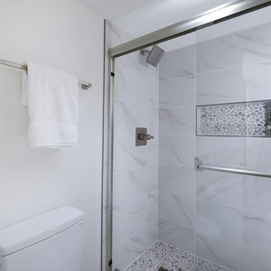 Stylish walk-in shower in the master features contemporary tile work, complemented by fresh white towels hanging nearby