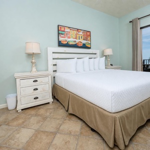 Serene master bedroom featuring a comfortable king bed, charming decor, and beachfront balcony access