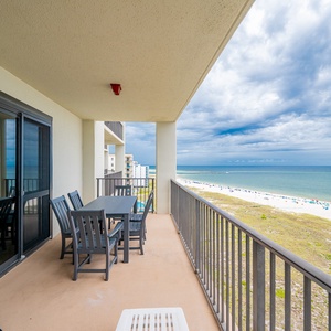 Spacious balcony features a dining table with seating and offers a view of the beach and gulf waters beyond