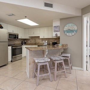 Bright kitchen area features granite countertops, stainless appliances, and a breakfast bar with seating