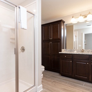 Enjoy a relaxing shower after a day at the beach in this guest bath with stylish cabinetry and spacious vanity