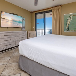 Cozy master bedroom with a large TV, stylish decor, and direct access to the beach balcony for fresh coastal air