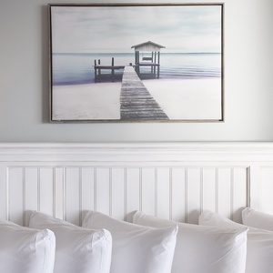 Adorn your space with a serene coastal print above a plush white pillow arrangement, inviting relaxation and tranquility