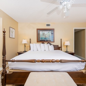 The master bedroom features a king bed with plush white linens, bedside lamps, and a tasteful nature artwork on the wall