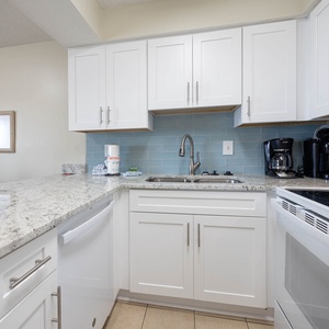 This kitchen features sleek white cabinetry, granite countertops, and modern appliances, perfect for preparing meals