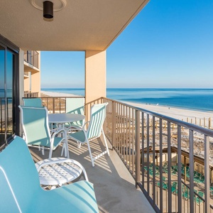 This balcony features turquoise seating and a table, perfect for enjoying breathtaking views of the tranquil shoreline