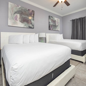 Relax in this guest room featuring two queen beds, modern decor, and a TV for your entertainment