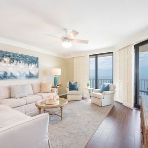 Soft cushions invite you to unwind in the living room while waves ripple beyond your balcony view