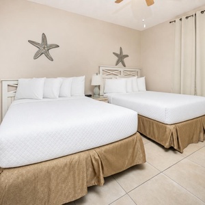 Rest comfortably in this guest bedroom with two double beds, soft linens, and charming coastal decor for a relaxing stay