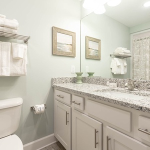 Freshen up with a shower in this guest bath, then dry off with stacked white towels from the rack before a beach stroll