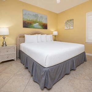 Brightly decorated bedroom featuring a king bed, bedside lamps, and artwork, creating a serene and inviting atmosphere