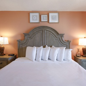 Elegant master bedroom featuring a king bed, warm orange walls, and stylish bedside lamps for a cozy ambiance