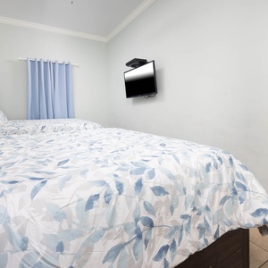 Guest bedroom featuring two queen beds with soft linens and a mounted TV for your entertainment