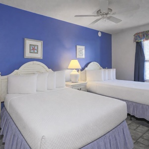 Brightly colored walls complement two double beds, creating a cheerful atmosphere in this inviting guest bedroom