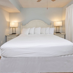 The master bedroom features a comfortable king bed, stylish lamps, and a playful fish-patterned shower curtain nearby