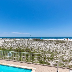 Bask in the sun by the pool with a beautiful view of the pristine beach and colorful umbrellas in the distance