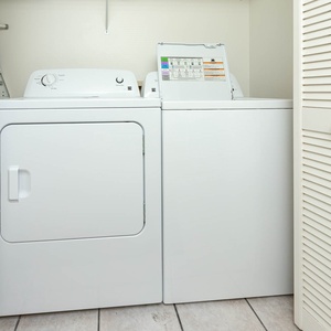 The laundry area features a stacked washer and dryer with a nearby ironing board for added convenience during your stay
