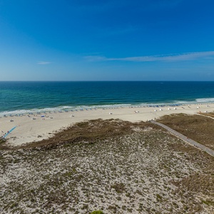 Rows of umbrella-covered seats line the shore as waves gently roll beneath the clear blue sky