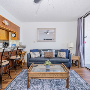This inviting living area features a cozy sofa, a glass coffee table, and a view of the beach through sliding glass doors