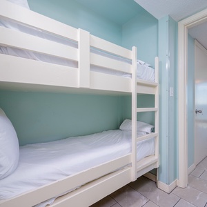 Cheerful bunk area with soft bedding and a calming teal backdrop, perfect for kids after a fun day