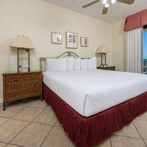 Master bedroom featuring a king bed, wicker nightstands, and sliding doors leading to a balcony with gulf views