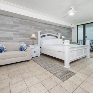 Spacious master suite featuring a plush king bed, stylish decor, and a cozy sofa chair with twin sleeper