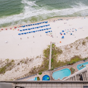 Breathtaking view of vibrant beach umbrellas and the pool area from a spacious balcony overlooking the sandy shore