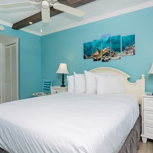 This inviting bedroom features a king bed, vibrant turquoise walls, and ocean-themed artwork for a refreshing retreat