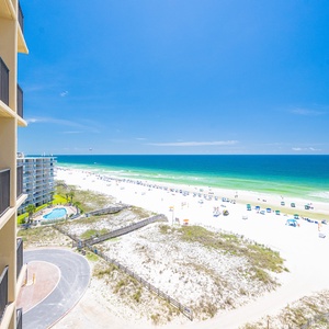 Expansive view of the beach with white sand and gentle waves under a clear blue sky, perfect for relaxation and fun