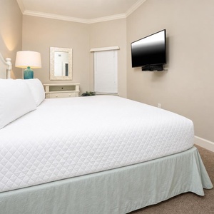 This cozy bedroom features a king bed, a wall-mounted TV, and soft lighting, creating a relaxing retreat for guests